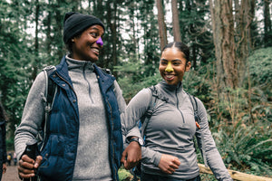 Two African American women in the woods wearing Nöz Nözscreen purple and yellow reef safe sunscreen on their nose